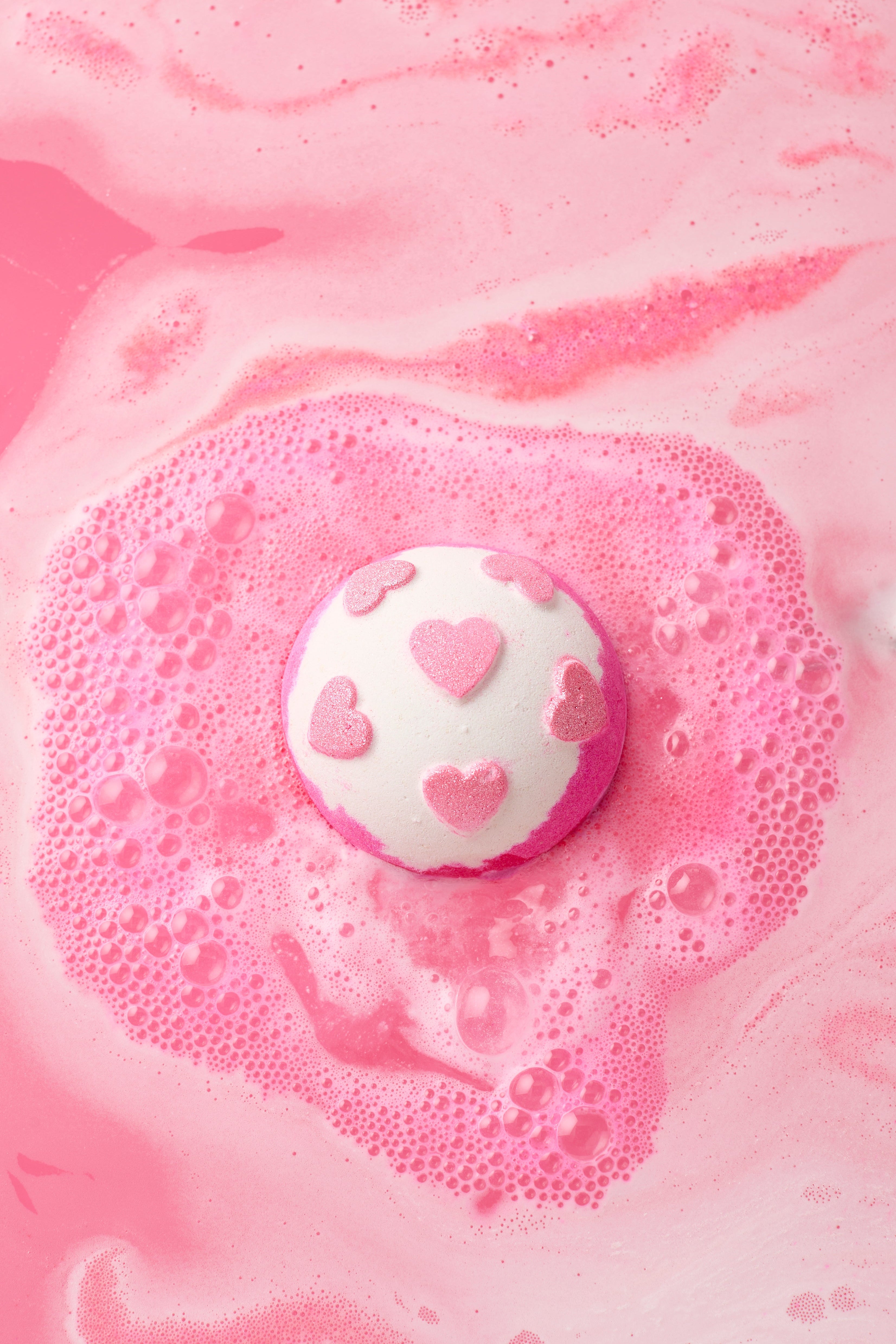 Pink bath bomb with heart design on a pink foam background