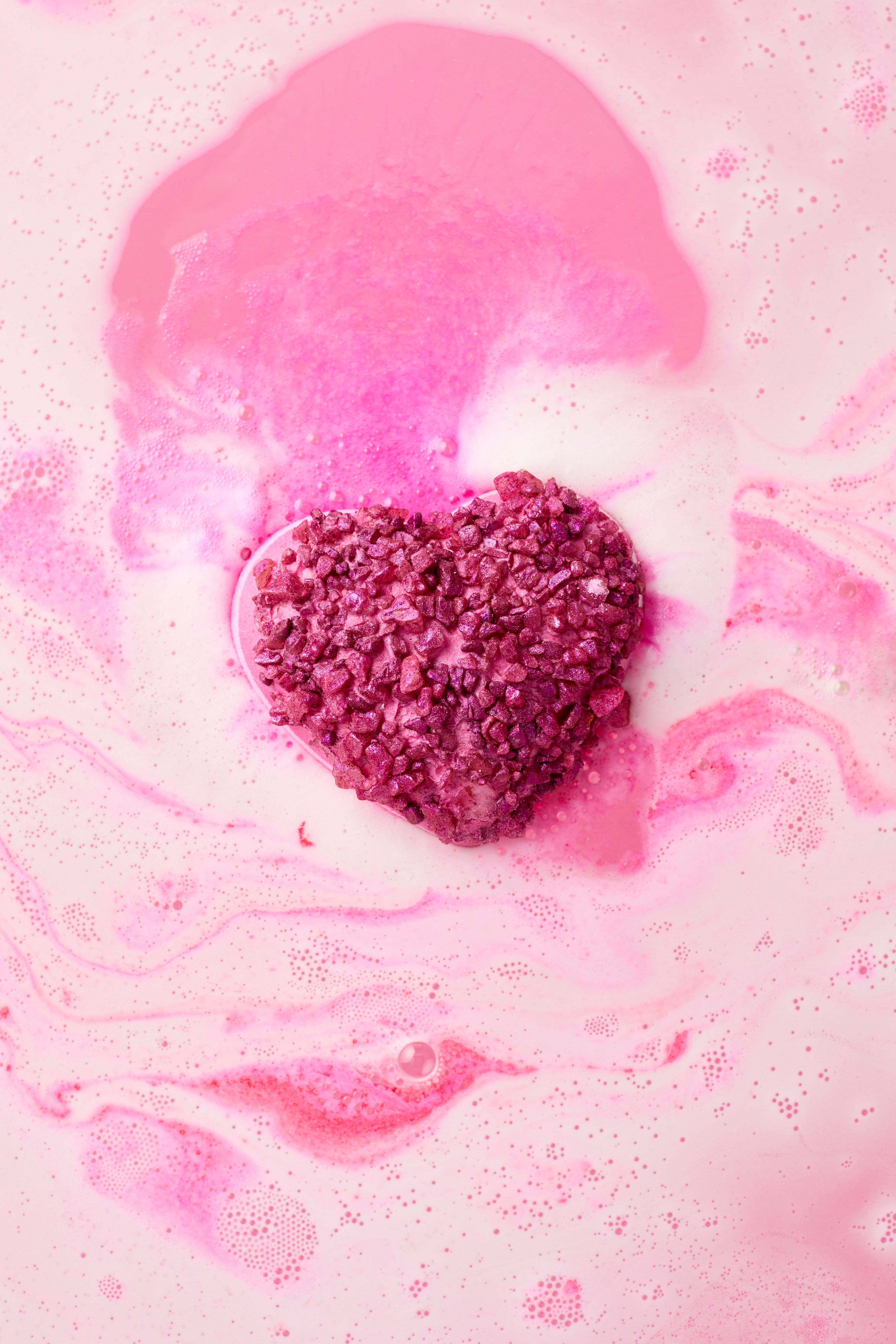 Pink and white foam with a purple heart-shaped object on a pink background