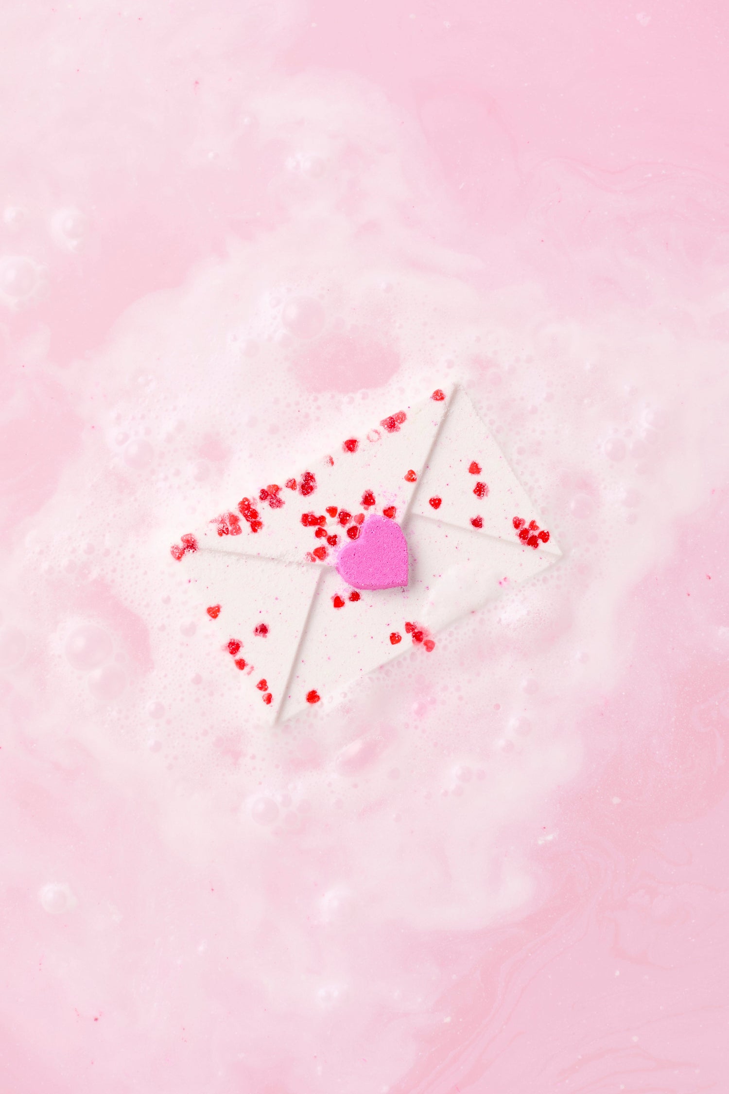 Heart-shaped lollipop with red candies on a pink background