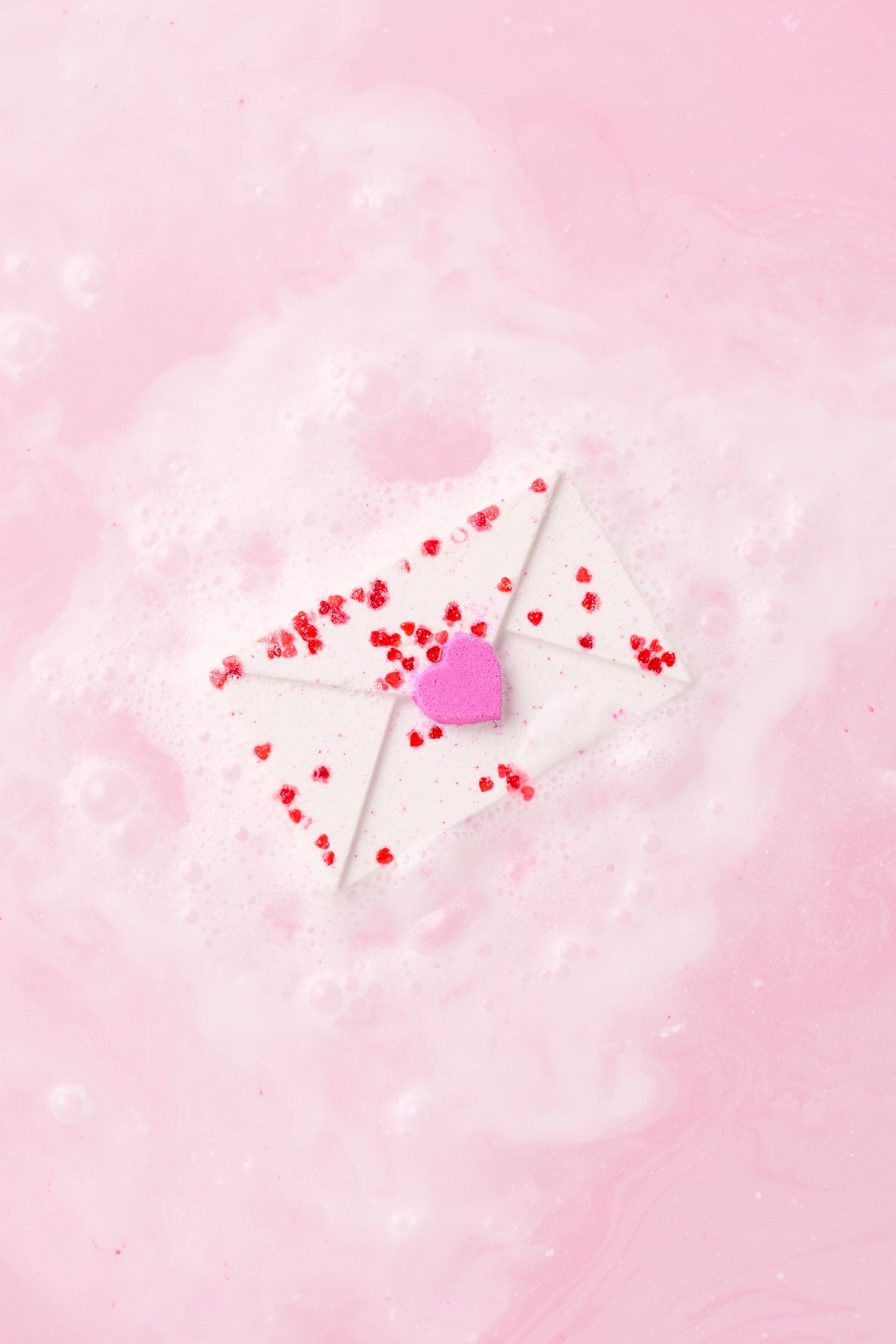 Heart-shaped lollipop with red candies on a pink background