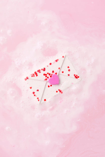 Heart-shaped lollipop with red candies on a pink background