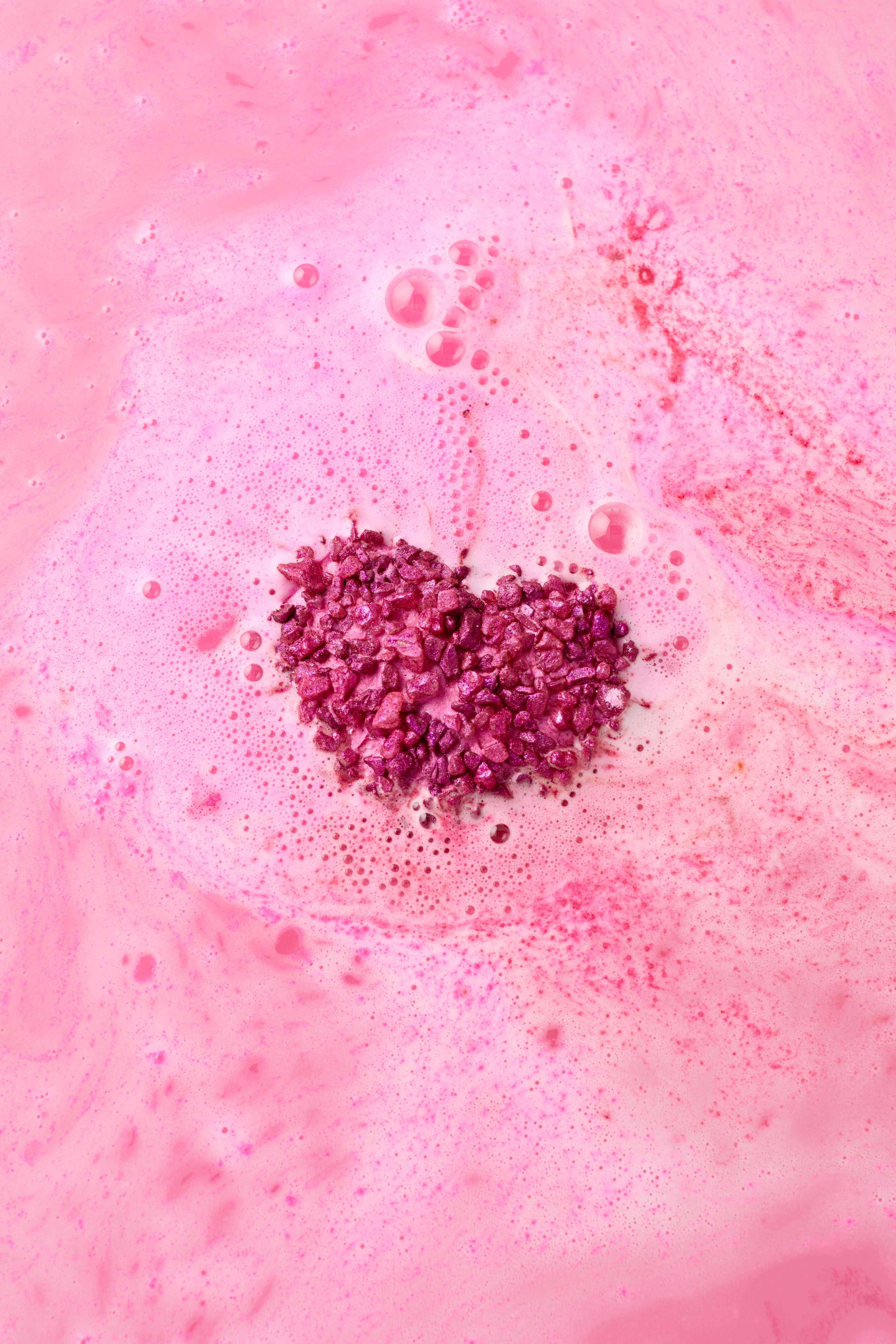 Pink bath bomb with a cluster of purple bath salts on top